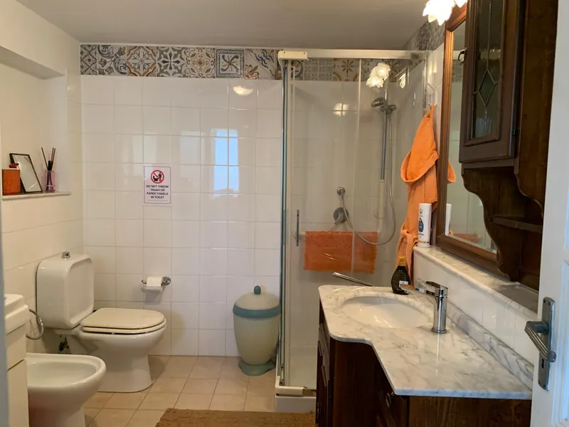 Bagno con cabina doccia, lavabo in marmo e fascia di maioliche