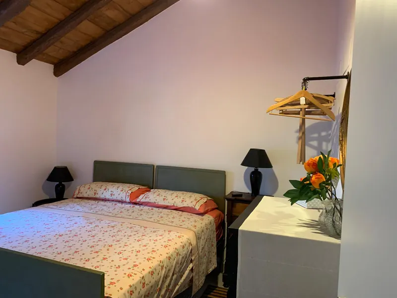 Camera matrimoniale con soffitto in legno a vista e comodini con lampade