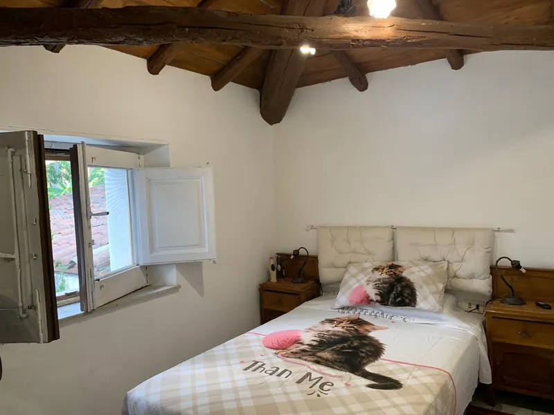 Seconda camera con grandi travi in legno e finestra sui tetti