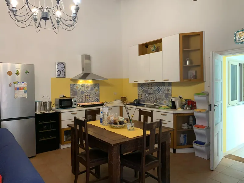 Cucina con maioliche siciliane, tavolo in legno e cantinetta per il vino
