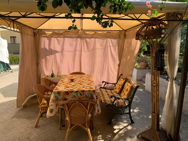 Gazebo con tavolo apparecchiato, sedie in vimini e panchina