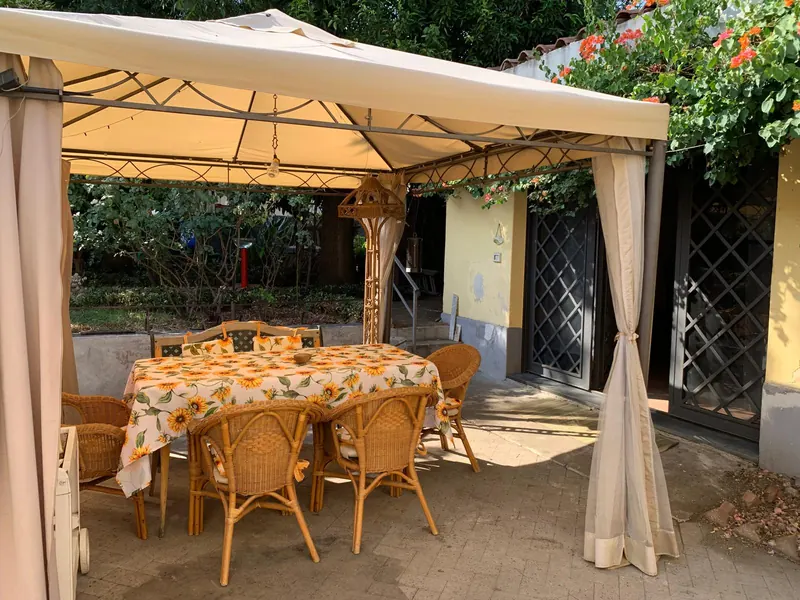 Gazebo in giardino con tavolo, sedie in vimini e bouganville in fiore